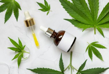 Üzerinde boş etiket ve yeşil kenevir sativa yakınında pipet olan damlatan şişe mermer masa manzaralı. Kozmetik Model, Uzayı Kopyala. Organik cilt bakım ürünü. Çevre dostu CBD oi