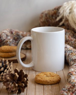 Çam kozalaklarının yanında beyaz kahve fincanı, kurabiyeler ve ahşap masaya örülmüş süveter. Yaklaş, kopyalama alanı. Kış Noel 'i. Bohem, etnik ya da İskandinav stili