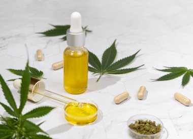 Yeşil kenevir yapraklarının yakınındaki şişeler, pipetler ve kapsüller, sert gölgeler. Organik cilt bakım ürünü. Çevre dostu CBD yağı. Alternatif sağlık aracı