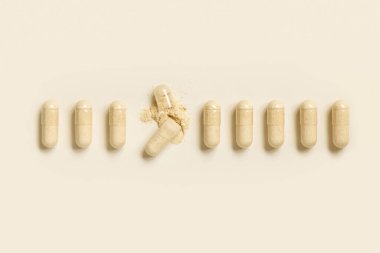 Açık bej renkli üst manzarada bej tozu göstermek için bir çizgi üzerinde tıbbi kapsüller. Koruyucu ilaçlar ve sağlık hizmetleri, beslenme takviyeleri ve vitaminler