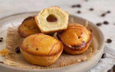 Yumurtalı krema ve vişneli reçelle doldurulmuş pastikciotto leccese pastası. Tipik bir apulian kahvaltısı için servis edilen tabakta tam ve yarım pasticiotties, yakın çekim. Kahve çekirdekleri ile süslenmiş bir masa.