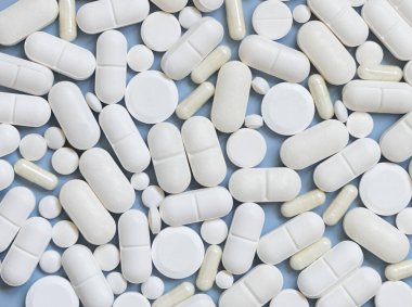 Beyaz tıbbi kapsüller ve açık mavi üst görüşlü hapların karışımı. Tıbbi tedavi için. Beslenme takviyeleri ve vitaminler alıyor. Çeşitli ilaç ürünleri.
