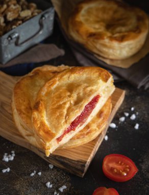 Beşamel soslu, domatesli ve mozzarella peynirli Rustico geleneksel puf böreği, karanlık bir masaya yakın. Salento, Lecce, İtalya 'dan geleneksel sokak yemekleri