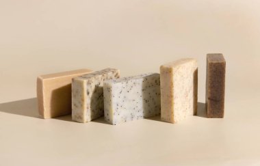 Açık bej üzerine doğal bitkisel bej ve kahverengi el yapımı sabunlar yakın plan, sert gölgeler. Spa ve cilt bakımı için hijyen ürünleri. Günlük rutinde organik el yapımı sopa kullanılıyor.