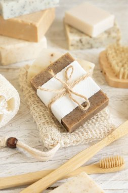 Doğal süngerler, bambu diş fırçaları ve pamuklu çubuklar gibi hijyen malzemelerinin yanında sabun koruyucu poşetlerinde bulunan organik el yapımı bej sabunlar. Doğal bitkisel ürünler