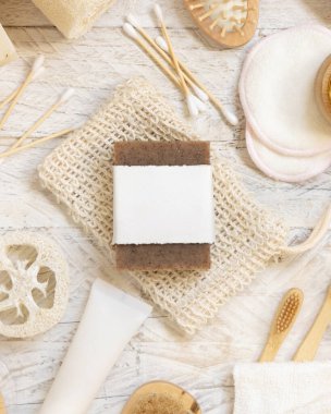 Doğal süngerler, fırçalar, bambu diş fırçaları, pamuklu çubuklar, üst görünüm, modelleme gibi hijyen malzemelerinin yanında boş etiketli organik el yapımı bej sabun çubuğu.