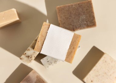 Açık bej üstten görünen bej ve kahverengi sabunlar, sert gölgeler, ambalaj modeli, kopyalama alanı. Yüz ve vücut bakımı için doğal bitki ürünleri. Organik el yapımı cilt bakımı ürünü