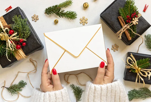 手与信封之间的圣诞装饰 黑色礼品盒和绿色冷杉树枝顶部的视野 空白信封造型 复制空间 圣诞或新年祝福 — 图库照片