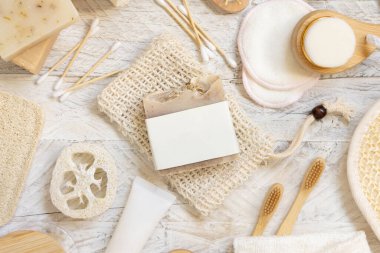 Doğal süngerler, fırçalar, bambu diş fırçaları, pamuklu çubuklar, üst görünüm, modelleme gibi hijyen malzemelerinin yanında boş etiketli organik el yapımı bej sabun çubuğu.