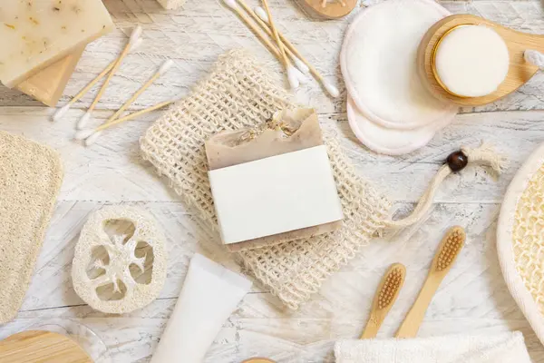 Doğal süngerler, fırçalar, bambu diş fırçaları, pamuklu çubuklar, üst görünüm, modelleme gibi hijyen malzemelerinin yanında boş etiketli organik el yapımı bej sabun çubuğu.