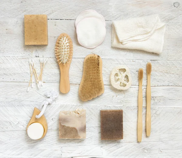 Sabun çubukları ve doğal hijyen ürünleri beyaz ahşap masa üzerinde üst görünüm. Havlu, doğal sünger ve fırça, bambu diş fırçası ve pamuk çubukları, üst manzara.