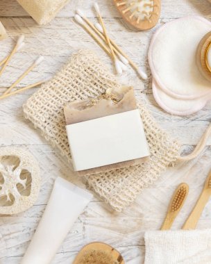 Doğal süngerler, fırçalar, bambu diş fırçaları, pamuklu çubuklar, üst görünüm, modelleme gibi hijyen malzemelerinin yanında boş etiketli organik el yapımı bej sabun çubuğu.