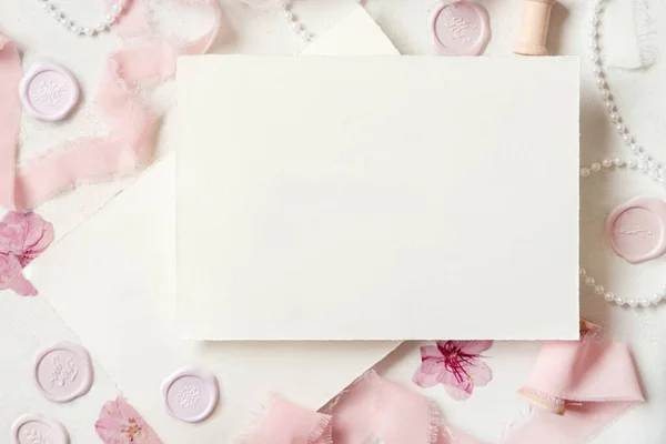 Karta Papierowa Pobliżu Różowych Dekoracji Uszczelki Jedwabne Wstążki Białym Stole — Zdjęcie stockowe