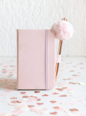 Beyaz masadaki kalplerin yanında kürk kalemli pembe kaplı defter. Düğün, Sevgililer Günü, Bahar ya da Anneler Günü için romantik bir model. Süt ürünleri için kız kitabı