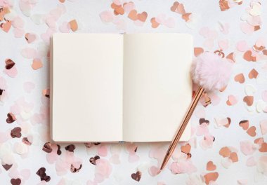 Beyaz masa manzarasında, kalplerin yanında ve kürk kalemle açılan defter. Düğün, Sevgililer, Bahar ya da Anneler Günü için romantik kızlar modeli. 