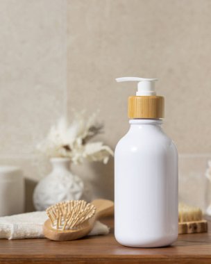 Güzellik ve kişisel bakım ürünlerinin yanında kozmetik şişesi banyodaki ahşap tezgahta bej duvara karşı yakın, sürdürülebilir kozmetik ambalaj modeli.