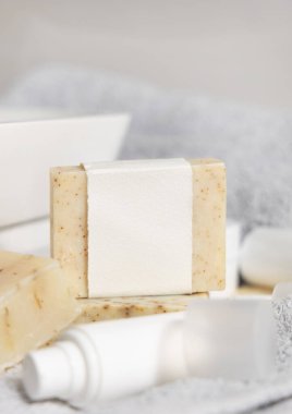 Havuz, havlu ve krem şişelerine karşı boş etiketli bej el yapımı sabun kalıbı. Kapatın, maket yapın. Tuvalette hijyen ve kişisel bakım ürünleriyle dolu hayat dolu bir sahne.