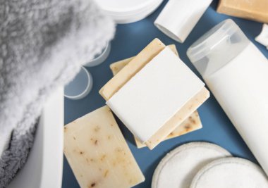Monstera fabrikası ve havza manzaralı mavi banyo tezgahında boş etiketli sabun çubuğu, ambalaj maketi, kopyalama alanı. Doğal temizlik ürünleri ve kozmetik ürünleri
