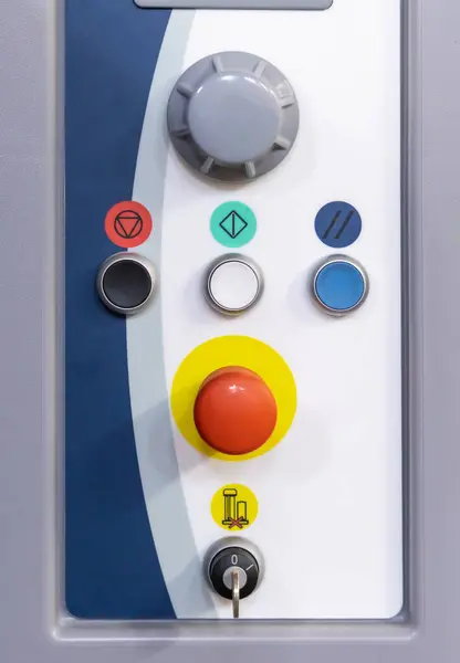 生産の機械操作のための大きい赤いボタンおよび他のボタンおよびスイッチが付いている灰色のコントロール パネル カラフルなシンボルを持っています このシステムは製造業の質そして一貫性を維持します ストック写真