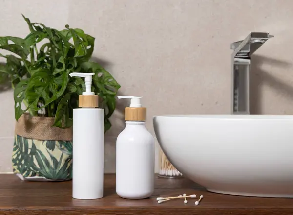 浴室的木制台面上有盆子附近的白色一个泵瓶 绿色的紫苏植物和棉签 可持续化妆品的现代场景 图库照片