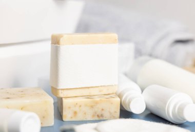 Havza ve krem şişelerine karşı boş etiketli bej el yapımı sabun kalıbı, yakın plan, maket. Tuvalette hijyen ve kişisel bakım ürünleriyle dolu hayat dolu bir sahne.