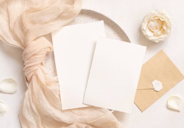 Krem tül kumaş düğümünün yakınındaki yatay kartlar çiçek ve zarf yakınındaki plakaların üzerinde, kopyalama alanı. Düğün kırtasiyesi modeli. Boş kartıyla romantik masa yeri