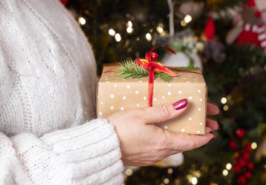 Beyaz kazaklı bir kadın Noel ağacı ışıklarına karşı elini uzatıyor. Kırmızı tırnaklı bir kız sıcak kahve ya da çay içiyor. Sıcak tatil ortamı