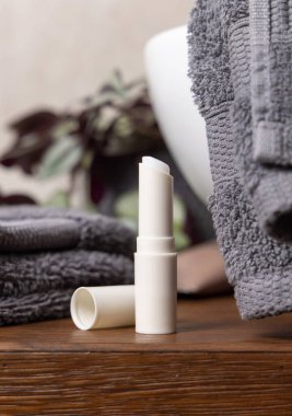 Banyo havlularının, kozmetik ürünlerinin ve damar lavabosunun yanında beyaz, boş dudak kremi çubuğu var. Güzellik ürünleriyle hayat dolu sahne, erkekler rutin cilt bakımı.