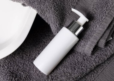 Koyu gri havlular üzerinde beyaz krem pompa şişesi banyo, üst manzara, ambalaj modeli. Doğal el yapımı kozmetik ürünü - losyon ya da sabun