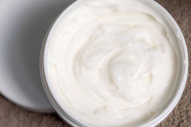 Kahverengi havluyla birlikte açık nemlendirici kavanozu, açık kozmetik kutusunda losyon. Yüz bakımı, Spa ve Sağlık Özü, krem dokusu