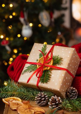 Kırmızı süveterin yanında fiyonklu hediye bo yanan şömine ve Noel ağacı ışıklarına karşı. Sıcak kış aile atmosferi, büyülü tatil zamanı. Noel hediyeleri paketleniyor