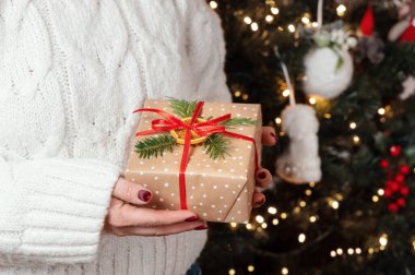 Beyaz kazaklı bir kadın Noel ağacı ışıklarına karşı elini uzatıyor. Kırmızı tırnaklı bir kız sıcak kahve ya da çay içiyor. Sıcak tatil ortamı