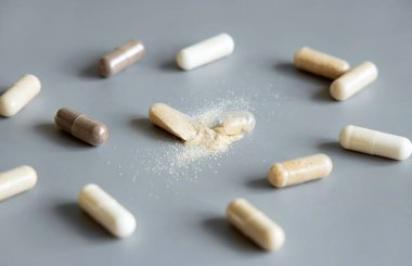 Tıbbi kapsüllerin çeşitleri, biri gri üzerine bej tozu göstermek için açıldı. Koruyucu ilaç ve sağlık, beslenme takviyeleri ve vitaminler. İlaç ürünleri.