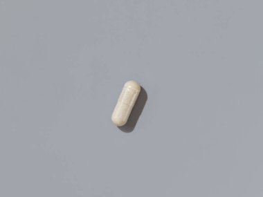 Gri üst manzaralı, koyu gölgeli bej tıbbi kapsül. Koruyucu ilaç ve sağlık, beslenme takviyeleri ve vitaminler. En düşük bileşim