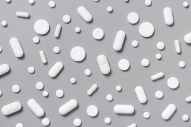 Beyaz tıbbi kapsüller ve hapların karışımı ve gri üst görüşlü bir kırmızı. İlaç ve sağlık sigortası, hastalık için ilaç almak. Çeşitli ilaç ürünleri.