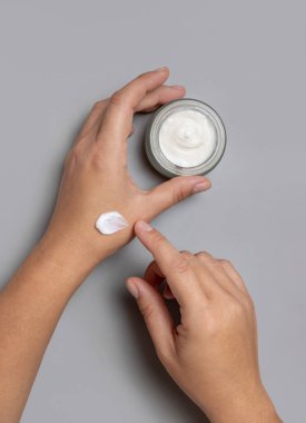 Kadının elinde koruyucu krem sürerken, diğer elinde kozmetik kavanozu tutarken, üstten bakıldığında gri. Kaplıcada güzellik ya da el bakımı prosedürü
