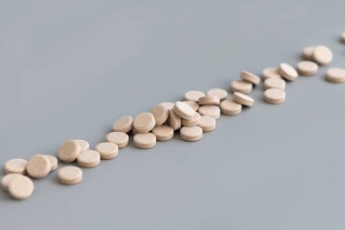 Gri çizgide bej bitkisel haplar yığını. Doğal beslenme takviyeleri, vitaminler, maca kökü hapları alıyorum. Alternatif tıp