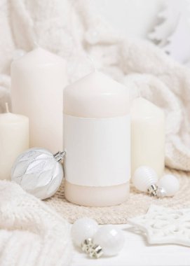 Beyaz örgü süveterin yanında boş etiketli sütun mumu, ahşap Noel süsü ve takılar, kopya alanı. Kış atmosferi kırsal ya da İskandinav stiliyle benzer.