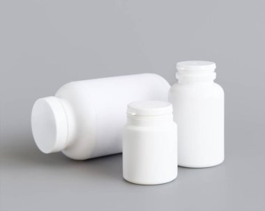 Beyaz plastik hap ya da kapsül şişeleri gri arka plana yakın çekim. Haplarınız ya da kapsülleriniz için ambalaj modeli, Helthcare için bitkisel takviye