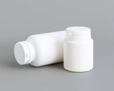 Beyaz plastik hap ya da kapsül şişeleri gri arka plana yakın çekim. Haplarınız ya da kapsülleriniz için ambalaj modeli, Helthcare için bitkisel takviye