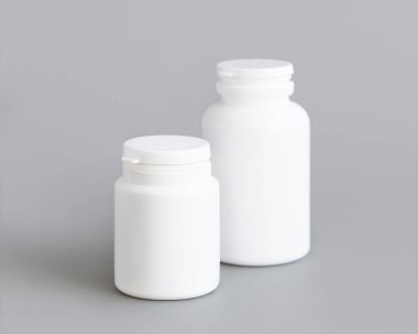 Beyaz plastik hap ya da kapsül şişeleri gri arka plana yakın çekim. Haplarınız ya da kapsülleriniz için ambalaj modeli, Helthcare için bitkisel takviye