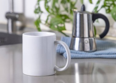 Gri mutfak masasındaki 11 ons beyaz kahve fincanı mavi İtalyan moka demliği ve yeşil bitki, maket. Kopyalama alanı olan tasarım şablonu