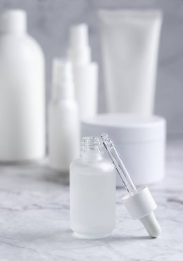 Pipette, kozmetik şişeleri ve kavanozların yanında beyaz mermer üzerine cam damlatan şişenin yanına kurulmuş. Kapatın, paketleme maketi. Doğal serum ya da özü. 