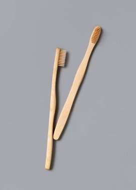 Açık gri arkaplan manzaralı iki biyolojik çözünebilir bambu diş fırçası, boşluğu kopyala. Sıfır atık ve plastik kavram yok