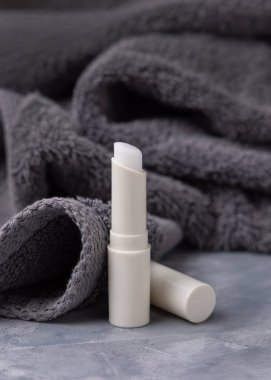 Koyu gri katlanmış havlulara beyaz, boş dudak kremi sürdüm yakın çekim, kozmetik ambalajlama, kopyalama alanı. Erkekler için lipcare güzellik ürünü günlük kişisel bakım