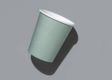 Tek kullanımlık yeşil kağıt bardaklar, gri arka planda, koyu gölgeli üstten görünüşlü, reklam alanı olan. Boş karton kahve fincanı. Plastik ve sürdürülebilir yaşam tarzı kavramı yok 