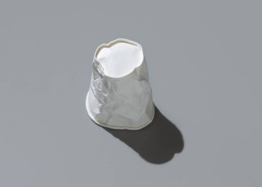 Kullanılmış ve buruşmuş tek kullanımlık beyaz bardakta gri bir üst görünüm, sert gölge, kopyalama alanı. Tüketim kavramı 