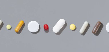 Beyaz, kırmızı ve sarı tıbbi kapsüller ve hapların karışımı gri üst görüş alanında. Tıbbi tedavi için. Beslenme takviyeleri ve vitaminler alıyor. Çeşitli ilaç ürünleri.