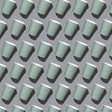 Gri üst görüntüde tek kullanımlık yeşil bardaklar, sert gölge, şablon, kopyalama alanı ile model. Boş karton kahve fincanları düz yerde. Tüketim kavramı 