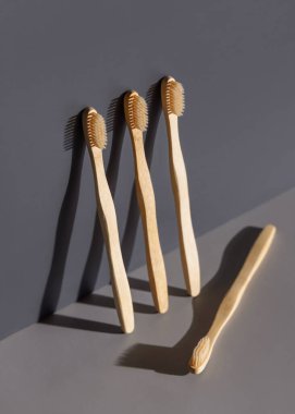 Gri arka plan üzerinde biyolojik olarak çözünebilir bambu diş fırçaları, koyu gölge yakın plan, model, negatif alan. Diş bakımı için doğal kişisel aksesuarlar, minimum stil estetiği 